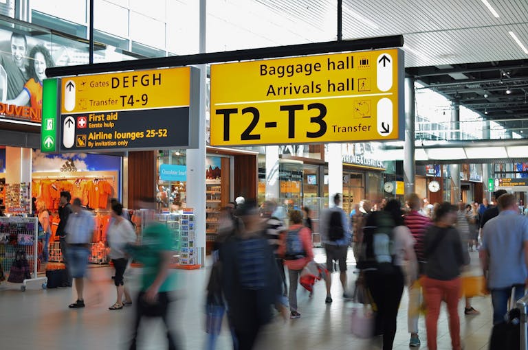 Crowded airport with motion blur and clear signage indicating baggage and arrival halls.